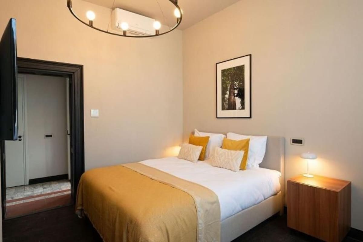 Habitación de hotel con cama, lámpara de noche y un cuadro en la pared.
