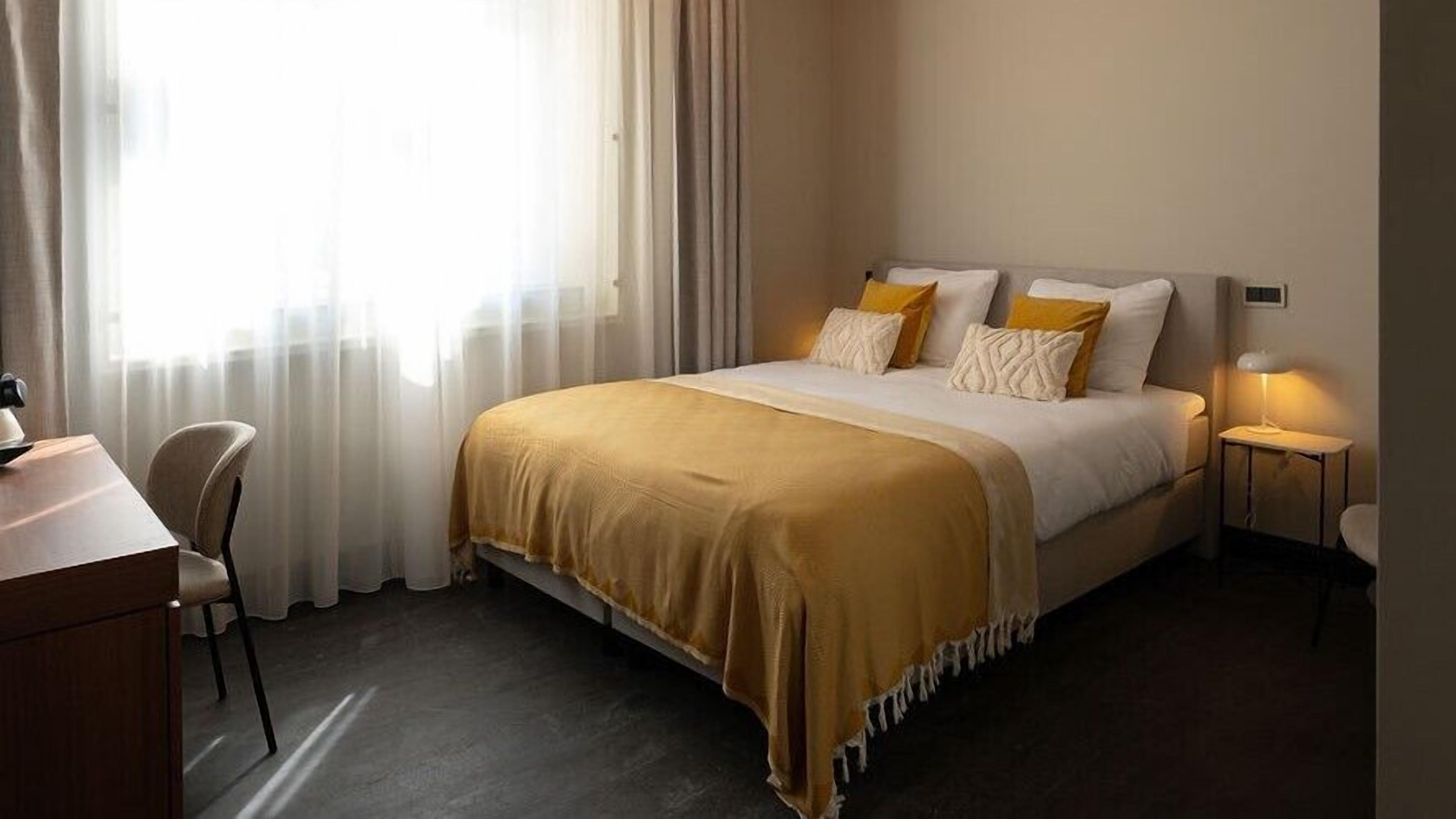 A hotel room with a bed, a desk, and a chair.
