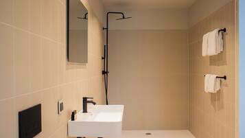 A modern bathroom with a white sink, a handheld showerhead, and a towel rack.