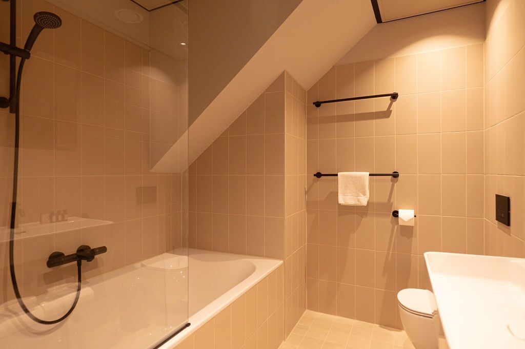 A modern bathroom with a glass-enclosed shower, a bathtub, and a toilet.
