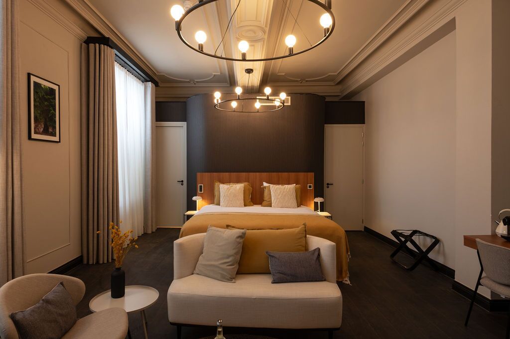 Una habitación de hotel con una cama grande, un sofá, una mesita y un candelabro.
