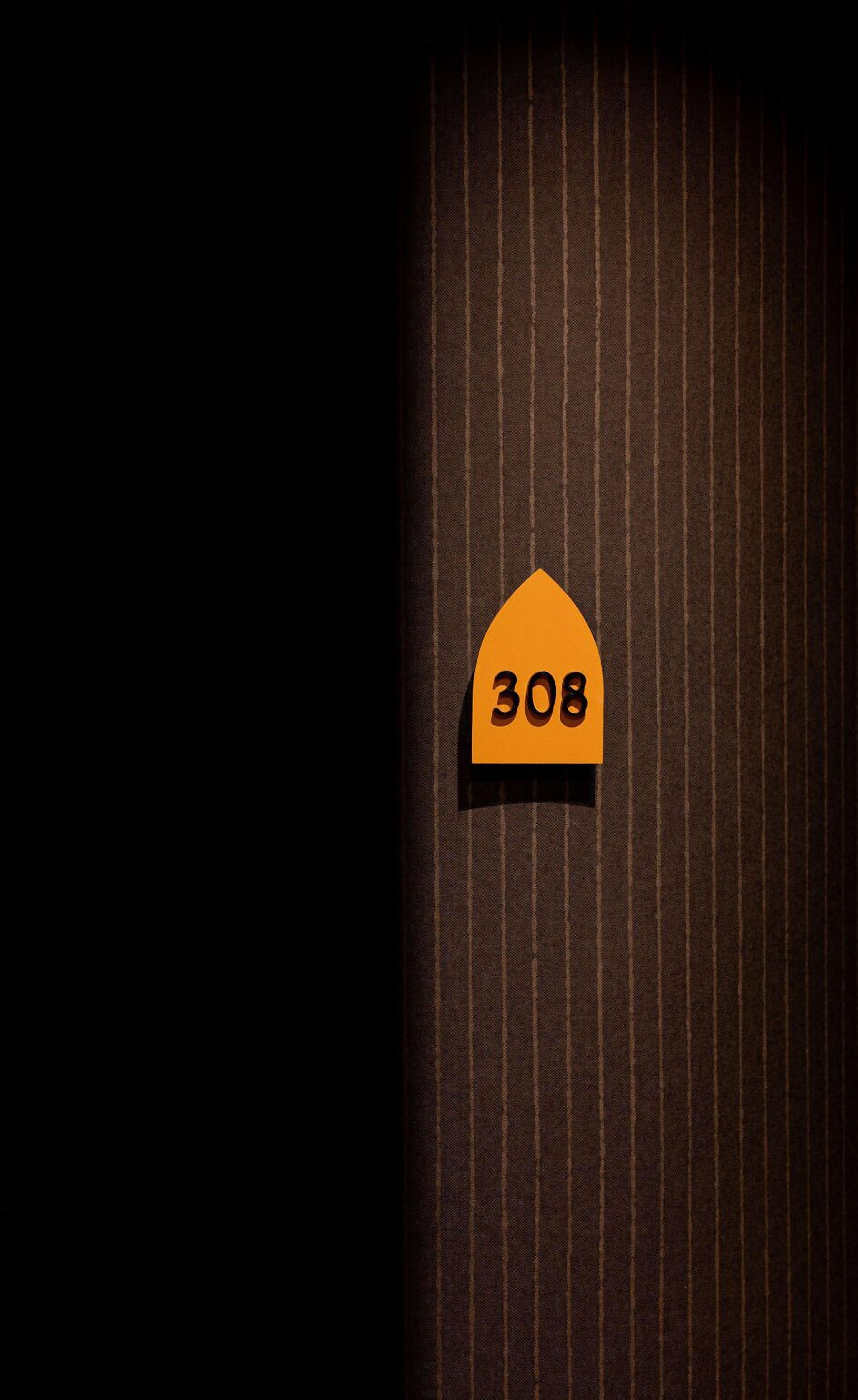 A dark room with a striped wall and a sign with the number 308.