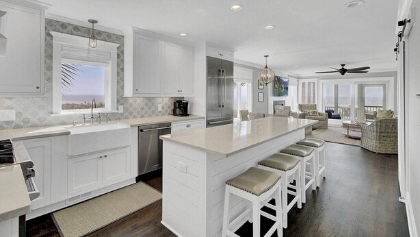 A spacious kitchen with a large island, white cabinetry, and a view to the outside. - Ocean 180 | True Oceanfront End Unit with 180° Views in Wild Dunes (Isle of Palms)