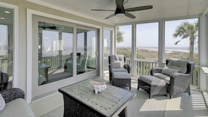 A sunlit balcony with wicker furniture, a ceiling fan, and a view of the beach. - Ocean 180 | True Oceanfront End Unit with 180° Views in Wild Dunes (Isle of Palms)