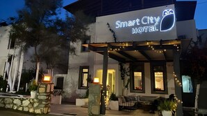 The exterior of the Smart City Hotel with a modern design, including a prominent neon sign, outdoor seating area, and well-maintained landscaping. - Smart City Suites Bodrum (Bodrum)