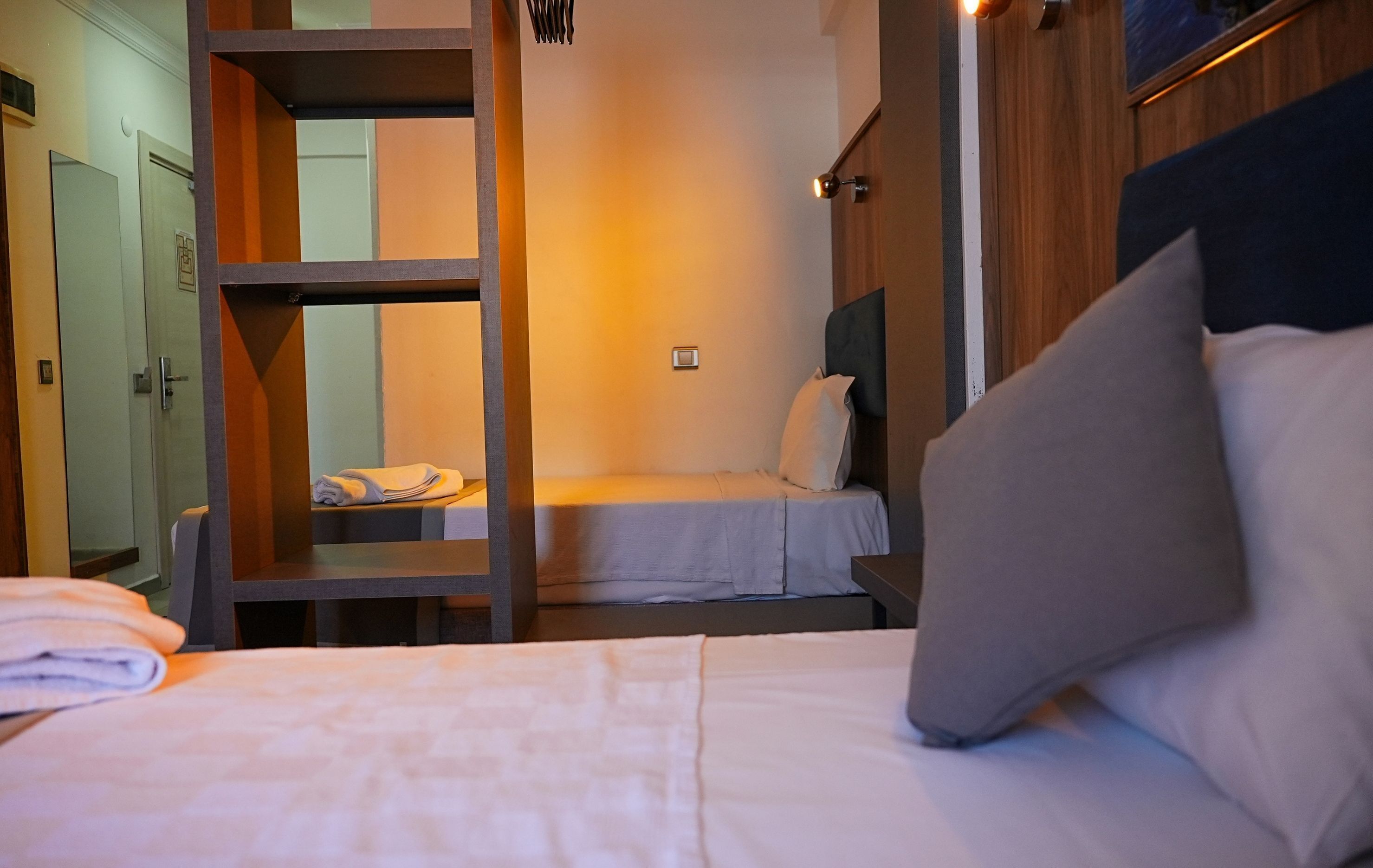 Een hotelkamer met twee bedden, een houten dressoir, een kledingkast en een nachtkastje.