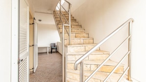 Eine Treppe mit Metallgeländern führt zu einer Empfangsebene mit einem Stuhl und einem Tisch.