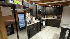 Una cocina moderna con armarios oscuros, electrodomésticos de acero inoxidable y salpicadero de azulejos.