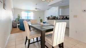 Un comedor moderno con una mesa de madera oscura, sillas a rayas y una lámpara colgante.