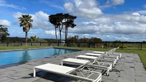 Un espace aménagé au bord de la piscine, avec des chaises longues et une vue dégagée sur la piscine.