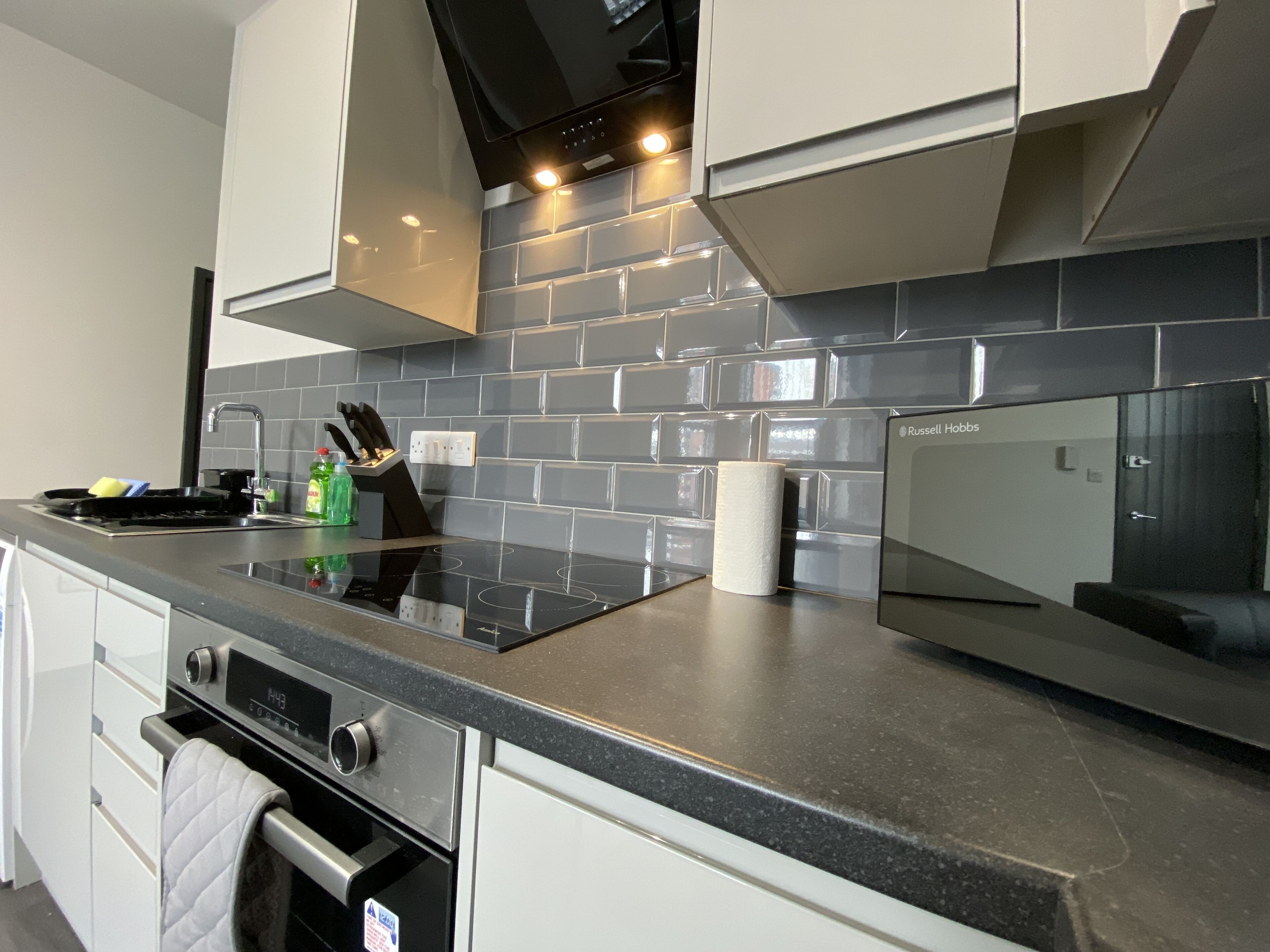 A modern kitchen with a black countertop, stainless steel appliances, and a tiled backsplash.
