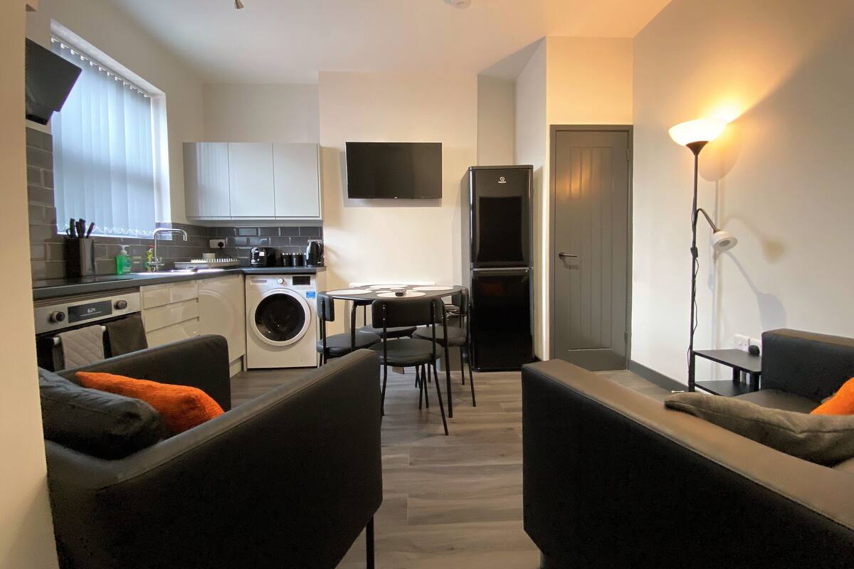 A compact living space with a kitchenette, a dining area, and a seating area with two sofas.
