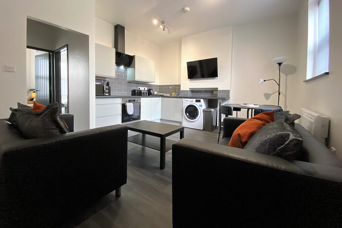 A modern living room with a sofa, a coffee table, and a TV mounted on the wall.