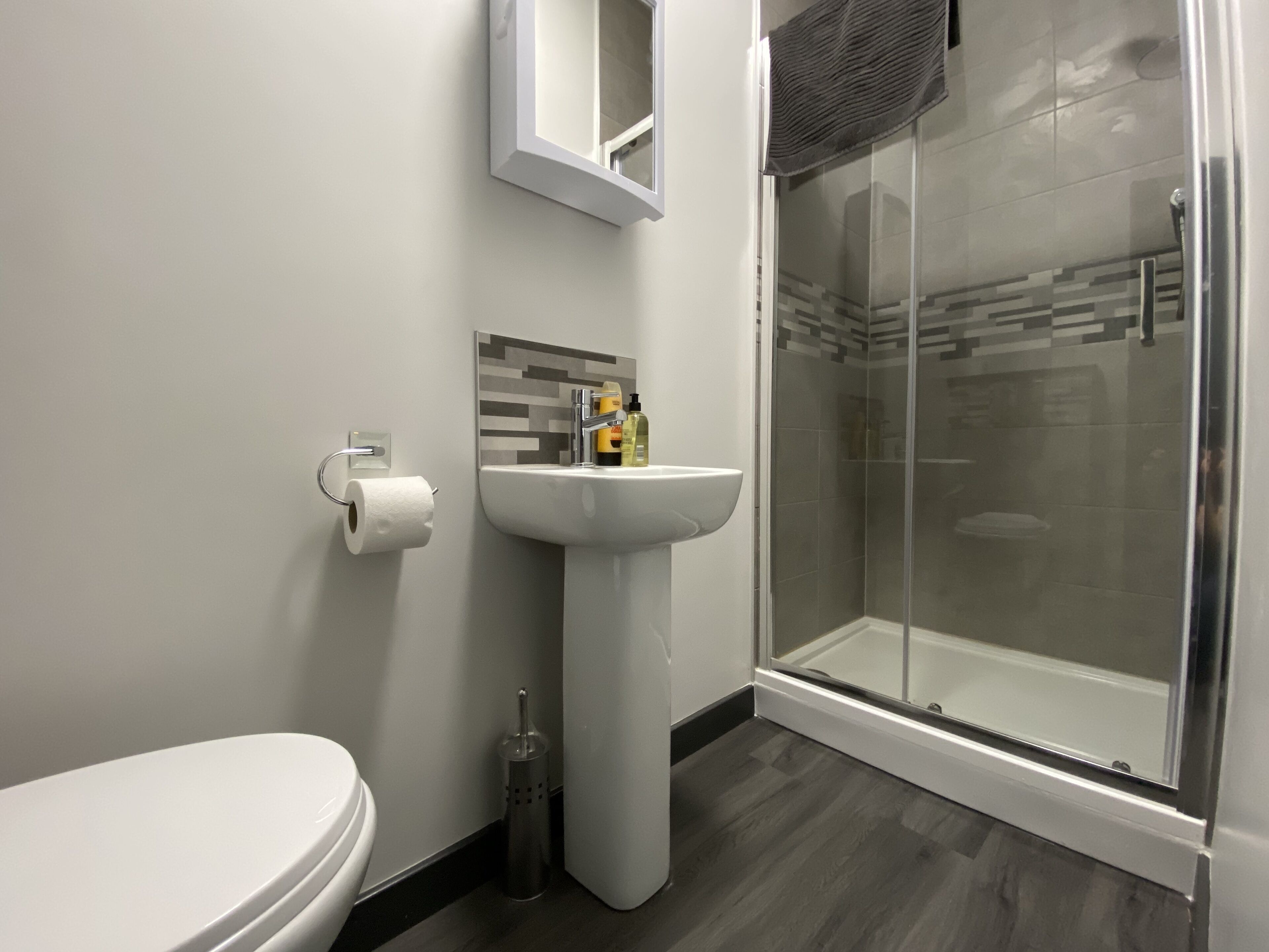 Een moderne badkamer met toilet, wastafel en douche met glazen wanden.