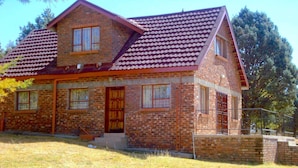 A two-story brick house with a red-tiled roof, a front porch, and a small front yard. - Khutsong Lodge (Maseru)