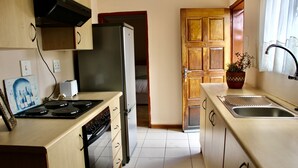 A compact kitchen with a stove, refrigerator, and sink. - Khutsong Lodge (Maseru)