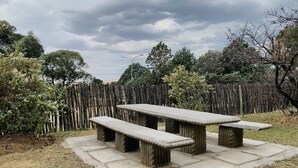 A stone picnic table with benches in a garden area. - Khutsong Lodge (Maseru)