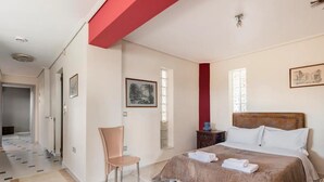 A bedroom with a bed, a chair, a nightstand, and a window. - Beautiful 1-bed Cottage in Megalopolis (Megalopolis)