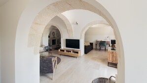 Un vaste espace de vie doté d’une grande télévision, de sièges confortables et d’une arche en pierre.