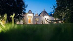 Une maison traditionnelle dotée d’une entrée bien éclairée, d’un hamac et offrant une vue dégagée sur la verdure environnante.