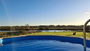 Une piscine avec vue sur un lac et la végétation environnante.
