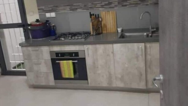 Een moderne keuken met witte kastjes, een ingebouwde kookplaat en een spoelbak.