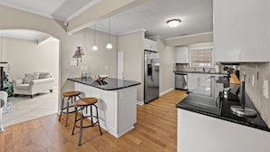 A modern kitchen with a central island, bar stools, and stainless steel appliances. - Pet Friendly Private House w/Pool & Game Room + Free Attraction Tickets! (North Myrtle Beach)