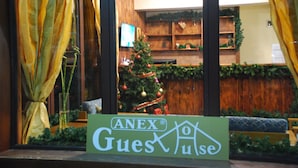 A hotel reception area with a Christmas tree, wooden decor, and a sign for ANEX Guesu. - Guest House Anex (Bansko)