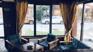 A cozy room with a large window, two chairs, a small table, and a radiator. - Guest House Anex (Bansko)