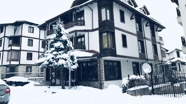 A multi-story building with a snow-covered roof and balconies. - Guest House Anex (Bansko)