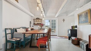 Een eetgedeelte met een houten tafel, stoelen en een bank. Achtergrond is een televisie en een open haard.