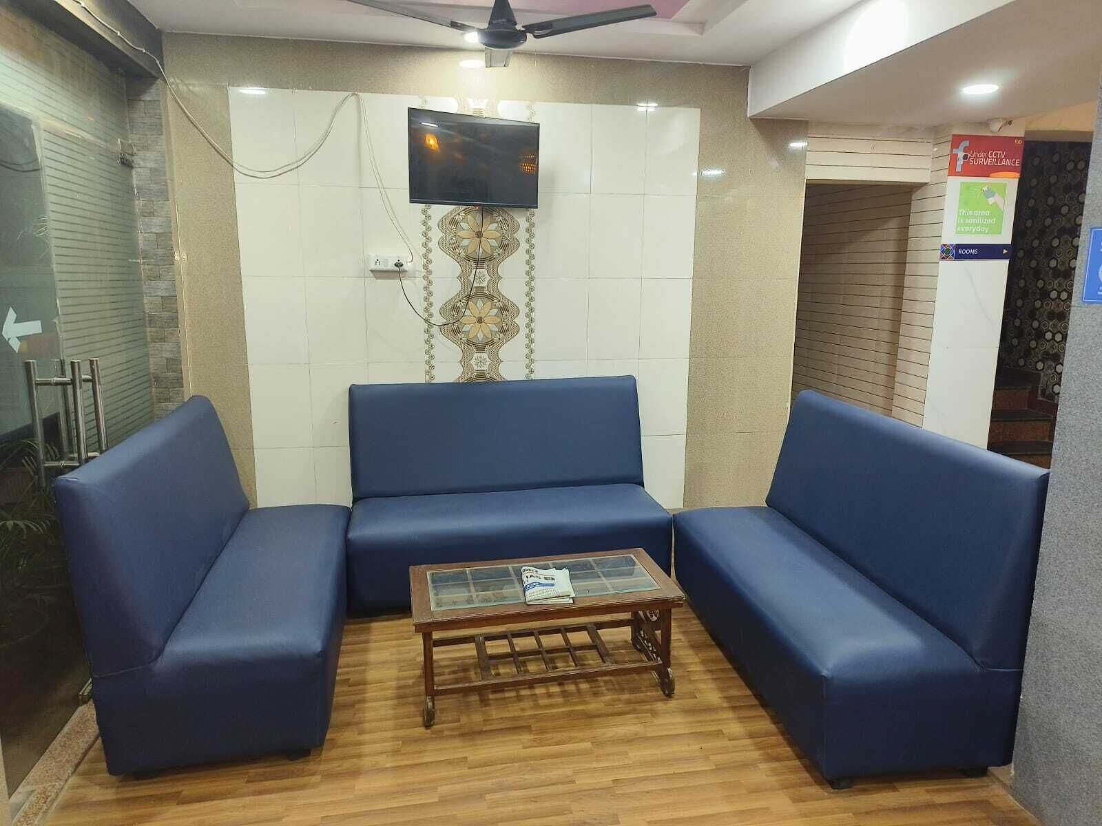 Un área de espera con sofás azules, una mesa de centro de madera y un televisor montado en la pared.