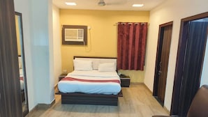 Une chambre à coucher avec un lit, une table de chevet, un rideau rouge et un ventilateur de plafond.