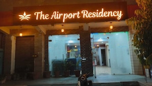 L’extérieur de l’hôtel The Airport Residency est agrémenté d’une enseigne au néon, de plantes en pot et d’un escalier menant à l’entrée.