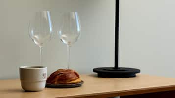 A wooden table with a white mug labeled "WOOD," a croissant, and two wine glasses.