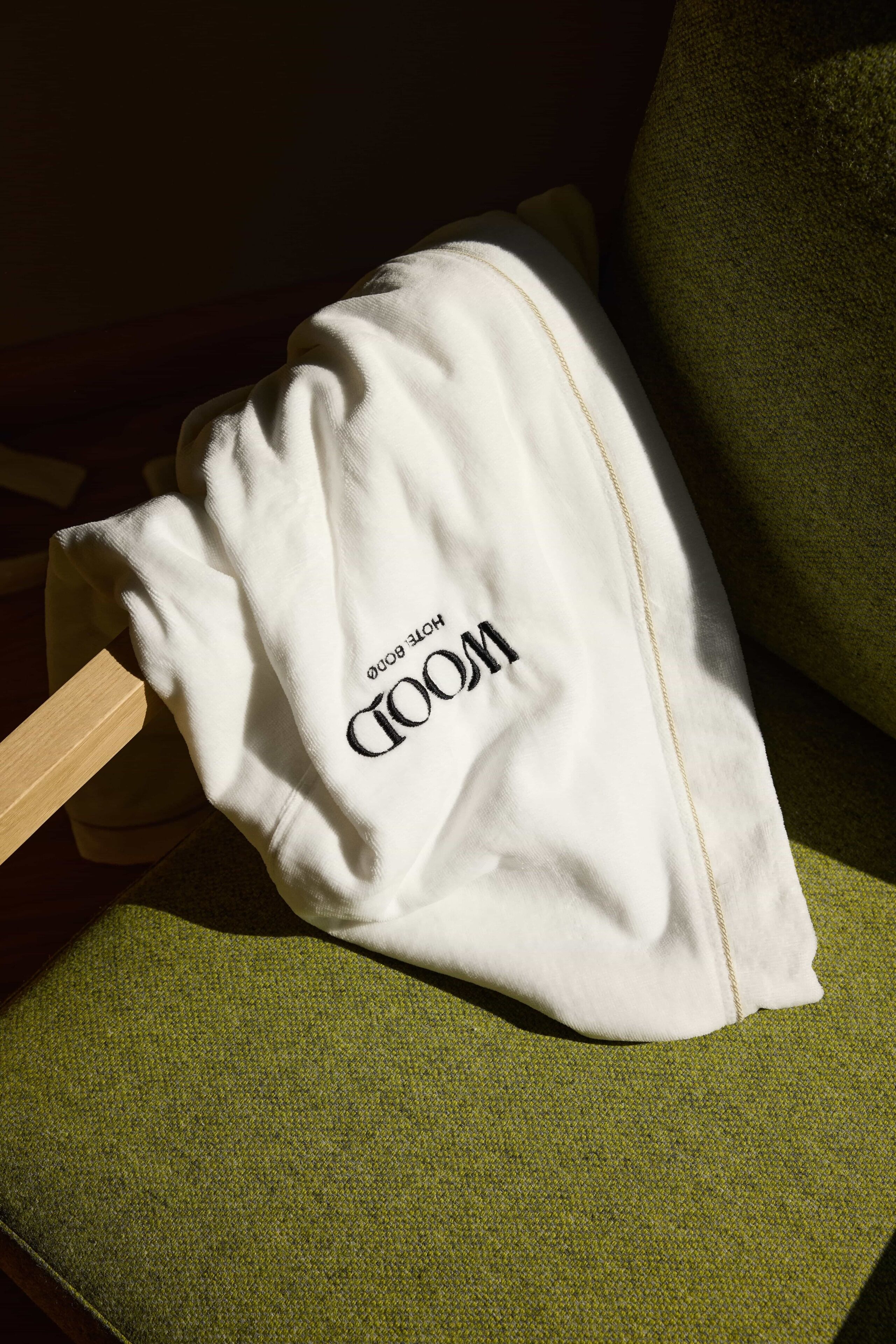 A white pillow with the text "HOTEL ROOM" on it, placed on a green cushioned chair.