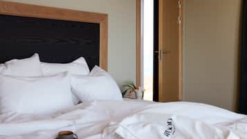A neatly made bed with white linens and a cup of coffee on it.