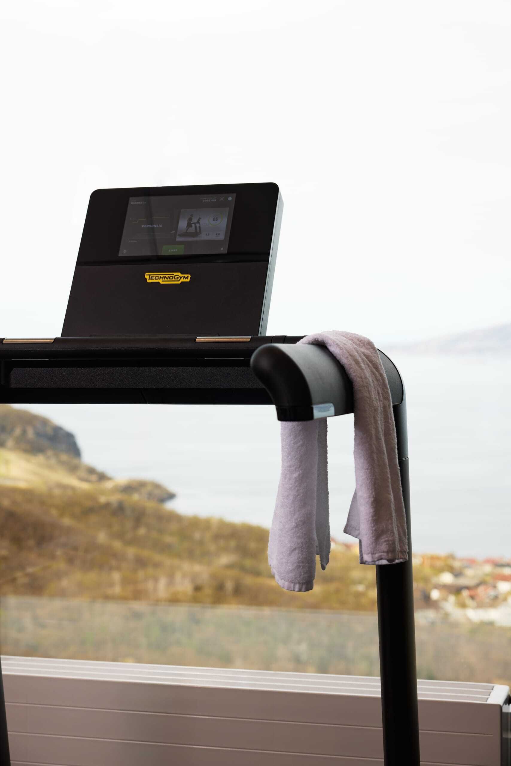 A treadmill with a digital display and a towel hanging on the side.