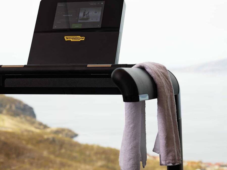 A treadmill with a digital display and a towel hanging on the side.