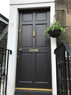 Uma porta da frente preta com maçaneta dourada e uma caixa de correio pequena acima.