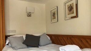A neatly made bed with white linens and pillows, a wooden headboard, and two framed pictures on the wall. - STYLISH APARTMENT WITH PRIVATE ROOF TERRACE (Edinburgh)