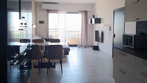 Un appartement moderne comprenant un coin repas, une cuisine et un balcon agrémenté de rideaux.