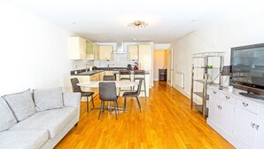 Eine moderne Wohnung mit Essbereich, Küche, Wohnzimmer und Fernseher.