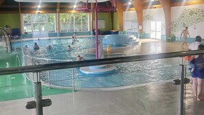 Une piscine intérieure dotée de plusieurs couloirs de nage, d’un plongeoir et d’un toboggan aquatique.