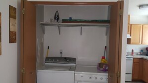 Ein Waschraum mit Waschmaschine, Trockner und Bügelbrett.