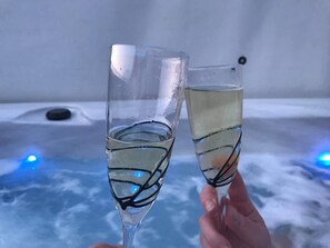 Two champagne flutes being held, one with a blue light reflection.
