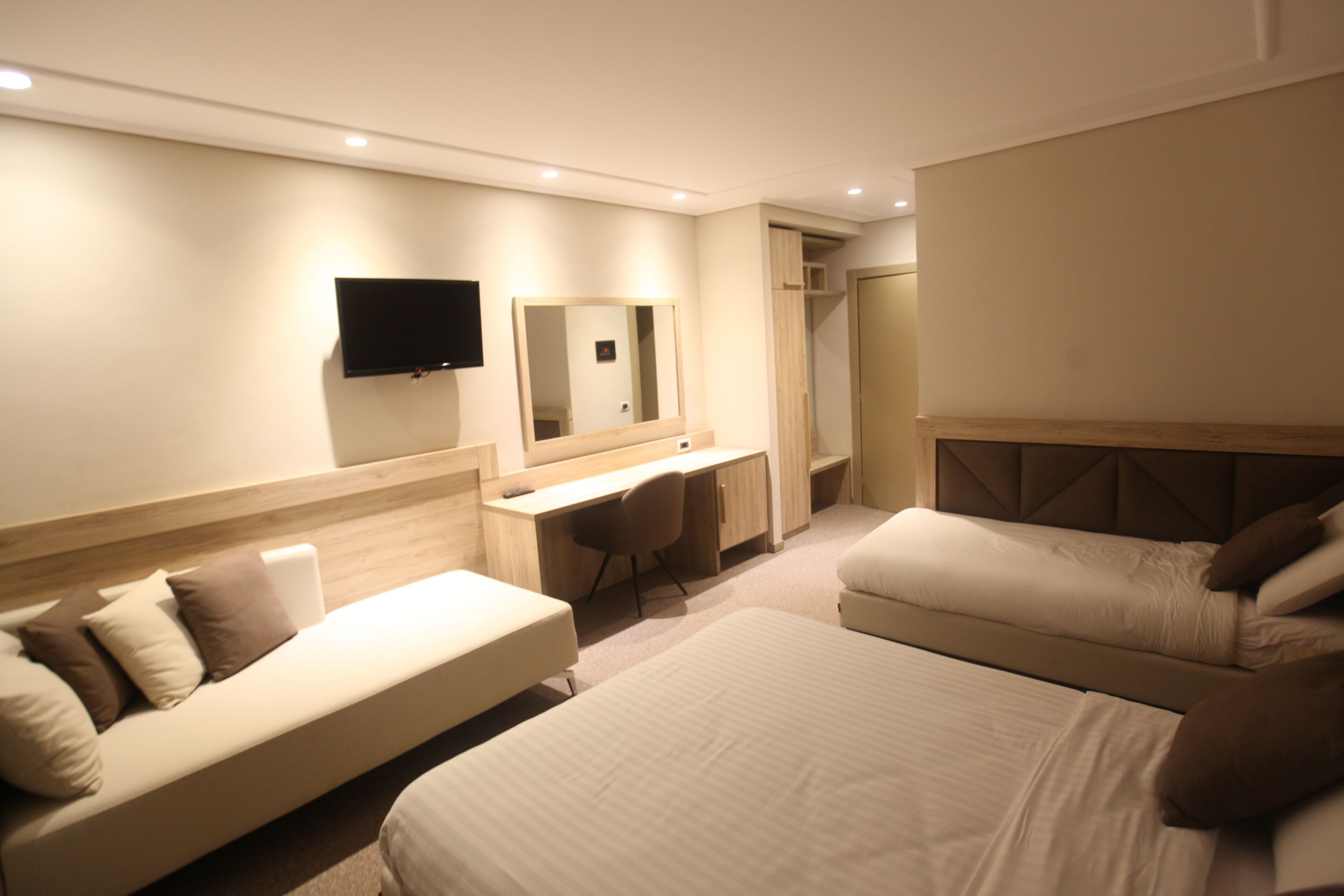 Ein modernes Hotelzimmer mit Bett, Sofa, Schreibtisch und Fernseher.