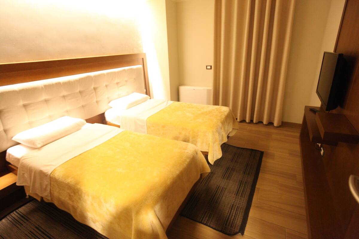 A hotel room with two beds, a television, and a radiator.