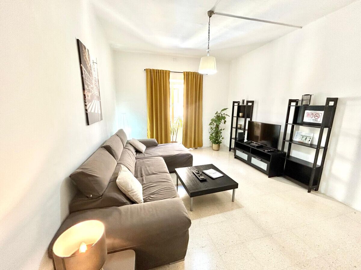 A modern living room with a sectional sofa, a coffee table, a TV stand, and a plant.