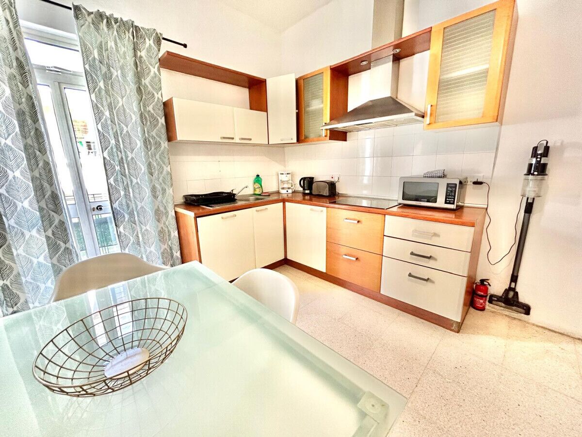A compact kitchen with white cabinets, a microwave, a coffee maker, and a fire extinguisher.